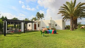 Una casa con patio, altalena e piccola piscina.