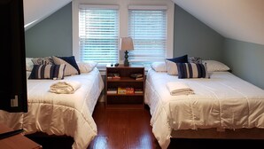Une chambre avec deux lits, une table de chevet et une lampe.