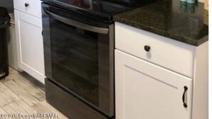 Une cuisine avec un four noir, un four à micro-ondes et des armoires blanches.