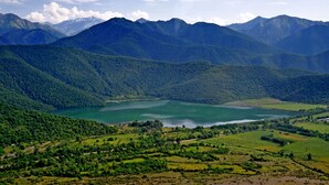 A mountainous landscape with a lake and surrounding fields. - About house......... (Quba)