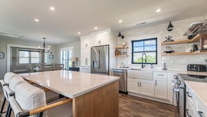 A modern kitchen with white cabinets, stainless steel appliances, and a large island. - Turtle Shack - Duck, Sea Tern, Oceanside, Beach 150 Yds, Pool, Pets OK, Flex Stays (Duck)