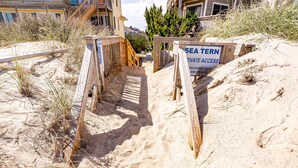 A sandy beach area with wooden barriers and a sign indicating private access to a sea terrace. - Turtle Shack - Duck, Sea Tern, Oceanside, Beach 150 Yds, Pool, Pets OK, Flex Stays (Duck)