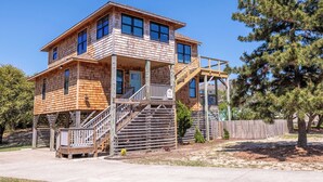 A two-story wooden house with a balcony and stairs leading to the second floor. - Turtle Shack - Duck, Sea Tern, Oceanside, Beach 150 Yds, Pool, Pets OK, Flex Stays (Duck)