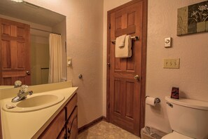 Un bagno con una porta in legno, un lavandino bianco e un water.