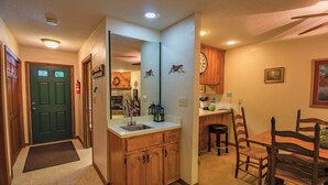Un interior de hogar con cocina, comedor y una puerta que da a otra habitación.