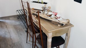 Een eetgedeelte met een houten tafel, vier stoelen, een kleine plant en een koffiezetapparaat.