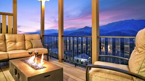 A balcony with a sofa, a fire feature, and a view of mountains. - DAZZLING Luxury Contemporary Cabin! PANORAMIC VIEWS! Theater! Fire Pits! Hot Tub (Gatlinburg)