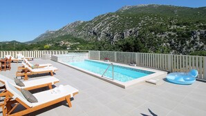 A rooftop pool with lounge chairs, a floating seat, and a mountainous backdrop. - Villa Remusic, Pool, whirlpool, Sauna,6 bedrooms, amazing landscape (Smolonje)