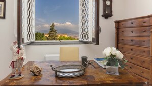 Ein Zimmer mit Holztisch, einer Dekofigur, einem Fenster mit Bergblick und einer Holzkommode.