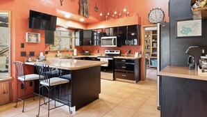 Uma cozinha com ilha central, armários pretos, micro-ondas e um relógio na parede.