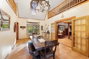 Un comedor amplio con una mesa y sillas de madera, un candelabro y vistas al exterior.
