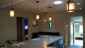 A modern kitchen with a long countertop, hanging pendant lights, and a decorative mirror. - Private house in a safe area, close to Nob Hill, UNM, Airport, Netflix, and KAFB (Albuquerque)