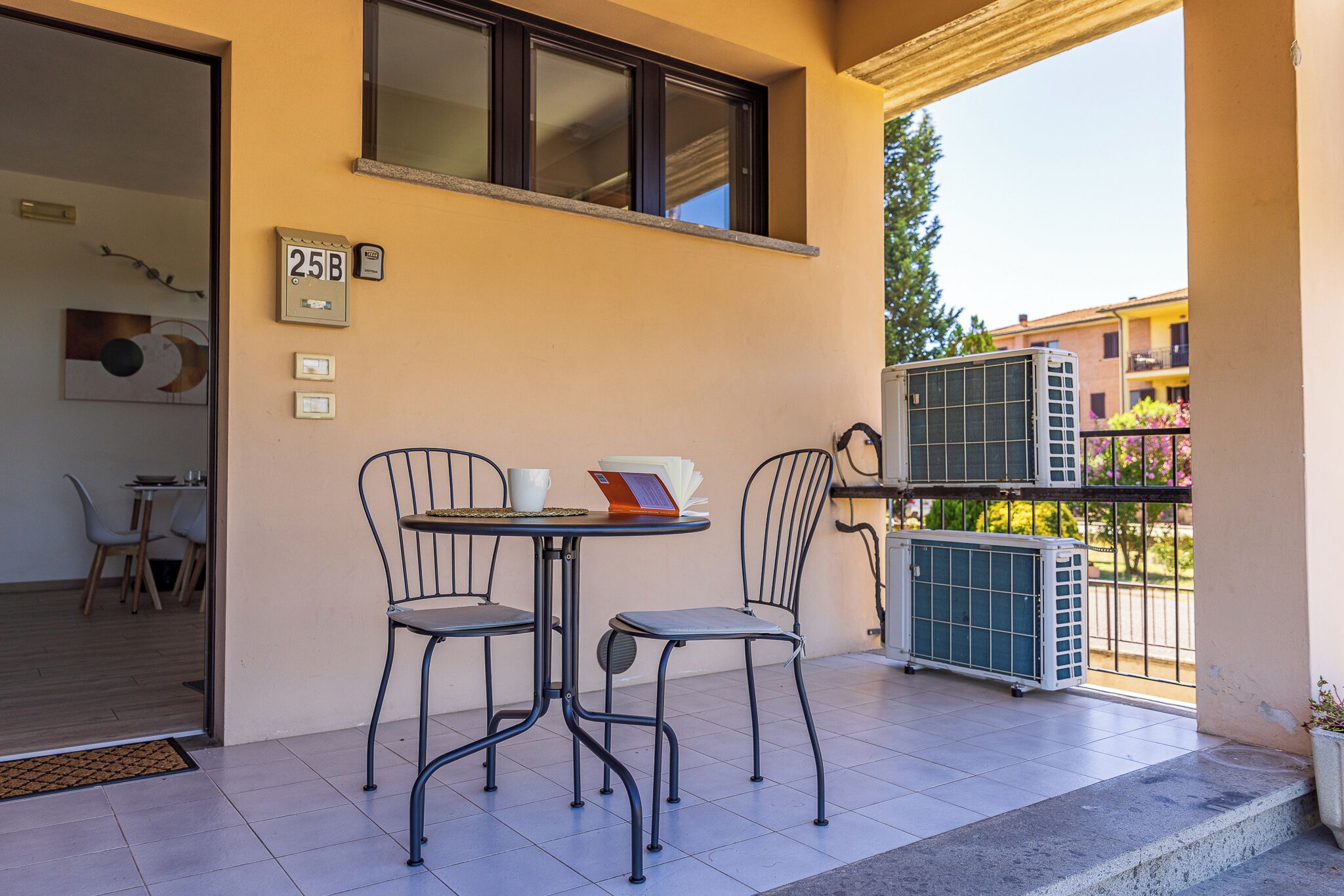 Ein Balkon mit zwei Metallstühlen, einem kleinen Tisch und einem Blumentopf.