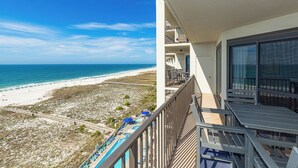 Un balcón con vista a la playa y una piscina.