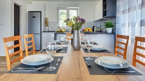 Una cocina moderna con una mesa de comedor para cuatro personas, un refrigerador y una ventana con vistas a zonas verdes.