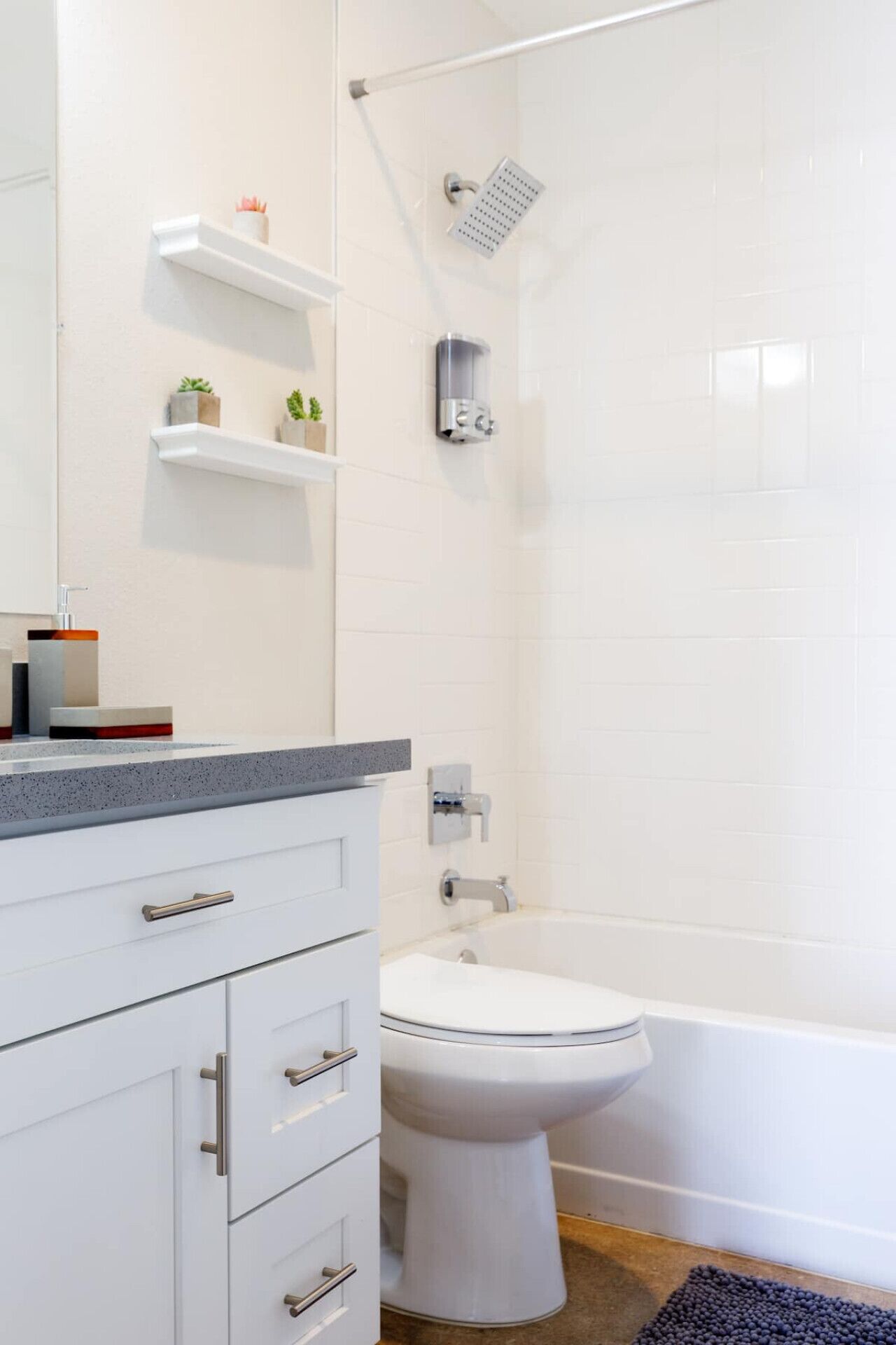 A modern bathroom with a toilet, shower, and vanity with drawers.