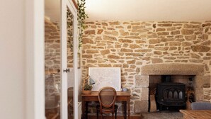A cozy room with a stone wall, a wooden desk, a chair, a fireplace, and a small table. - Ty Glaz Lilia (Plouguerneau)