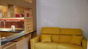 Una cucina moderna con lavello integrato, pensili in legno e un divano giallo.