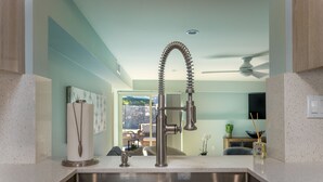 A modern kitchen with a stainless steel sink, a flexible faucet, and a ceiling fan. - Travel Back in Time to this Gorgeous 1950's Remodel (La Quinta,)