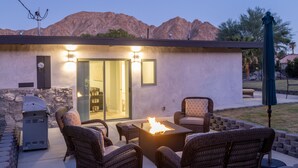 An outdoor patio with wicker furniture, a grill, and a fire feature. - Travel Back in Time to this Gorgeous 1950's Remodel (La Quinta,)