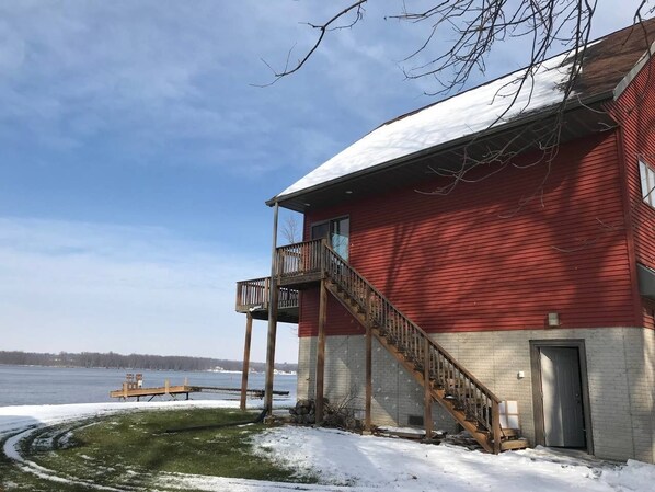 A red building with a balcony and a staircase leading to a door. - Mississippi River House (East Moline)