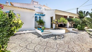 A building with a tiled courtyard, a white facade, and blue accents.