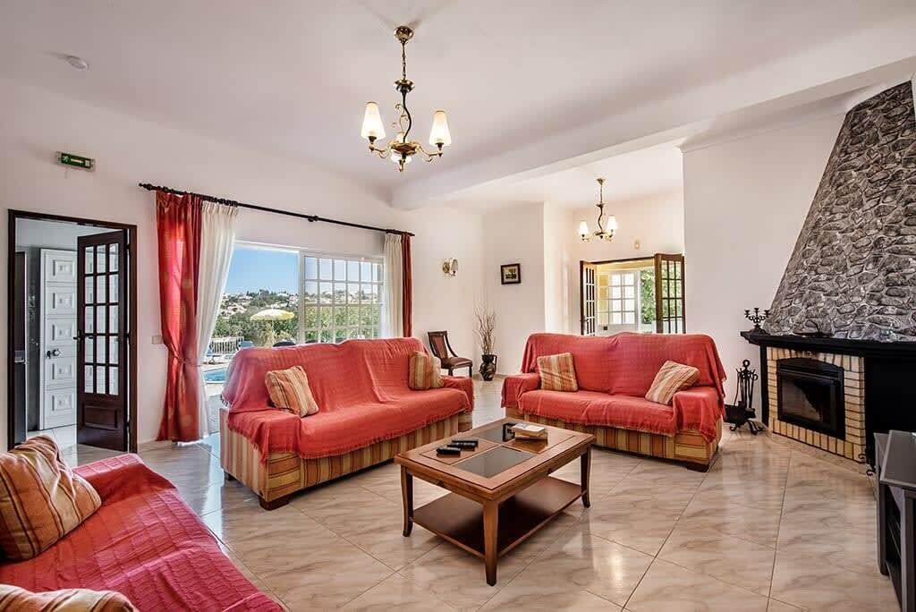 A spacious living room with two red sofas, a wooden coffee table, and a stone fireplace.
