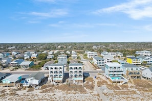 Un quartier résidentiel situé sur la côte, avec des immeubles à plusieurs étages, dont certains sont dotés de balcons et donnent accès à la plage.
