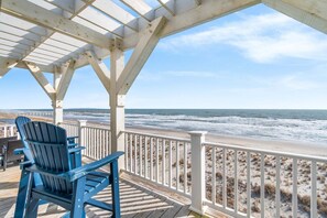 A covered deck with a view of the ocean and beach. - Just Add Water - Spacious 7BR oceanfront home in Oak Island, perfect for 19 guests. (Oak Island)