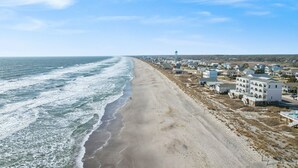 Un pueblo costero con propiedades frente a la playa, una playa de arena y un cielo despejado.