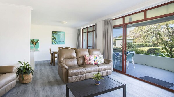 A spacious living room with a leather sofa, a coffee table, and a dining area.