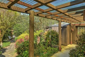 A covered garden area with a wooden pergola structure, a stone pathway, and various plants. - Redwood | Japanese-Inspired Retreat by the Sea (Sea Ranch)
