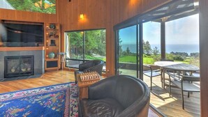 A modern interior with a fireplace, a chessboard, and a view of the outdoors. - Redwood | Japanese-Inspired Retreat by the Sea (Sea Ranch)