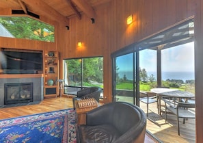 A modern interior with a fireplace, a chessboard, and a view of the outdoors. - Redwood | Japanese-Inspired Retreat by the Sea (Sea Ranch)