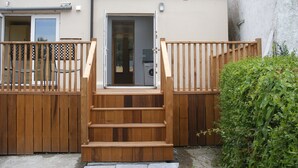 A wooden staircase leading to a door, surrounded by a fence and a hedge. - Cooraclare apartment (Cooraclare)