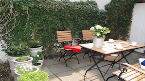 An outdoor patio with a wooden table and chairs, surrounded by potted plants and a white fence. - "Strandläufer" Vacation Rental in Kappeln (Kappeln)