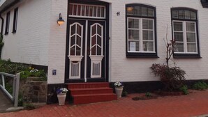 A traditional white building with a steep gabled roof, a prominent entrance with double doors, and a small porch area. - "Strandläufer" Vacation Rental in Kappeln (Kappeln)