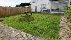 A backyard with a picnic table, a wooden fence, and a house with a glass door. - 5 bedroom accommodation in East Ogwell, near Newton Abbot (East Ogwell, near Newton Abbot)