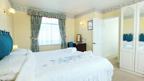 A hotel room with a large bed, a dresser, a mirror, and a door. - 5 bedroom accommodation in East Ogwell, near Newton Abbot (East Ogwell, near Newton Abbot)