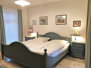 Classic bedroom with a single bed, nightstands, and framed artwork.