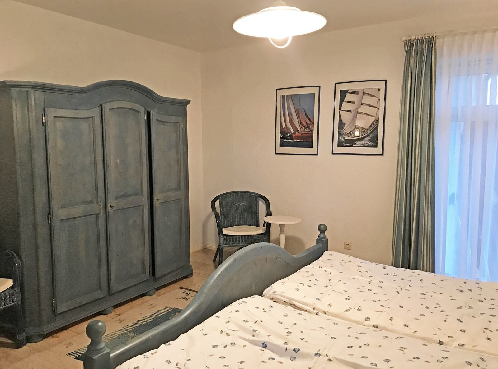 Un dormitorio con una cama, un armario, una silla y dos cuadros en la pared.