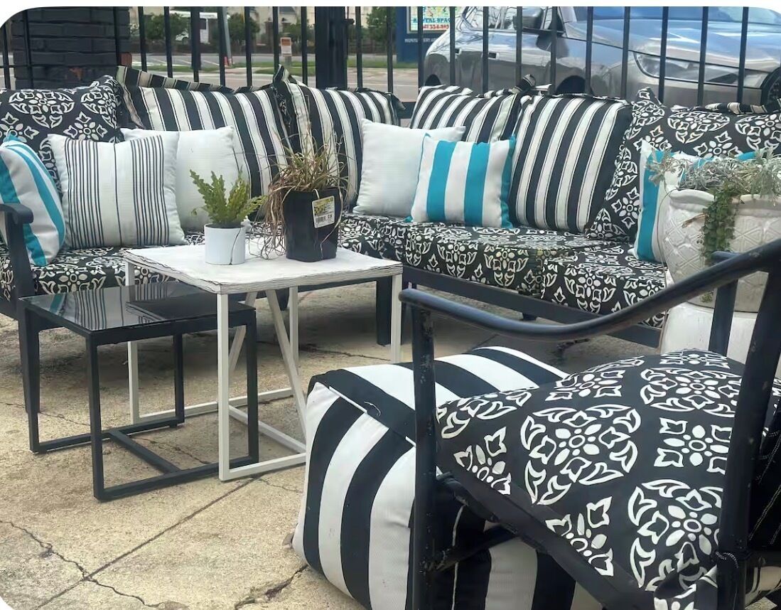 An outdoor seating area with black and white patterned sofas, a small table, and potted plants.