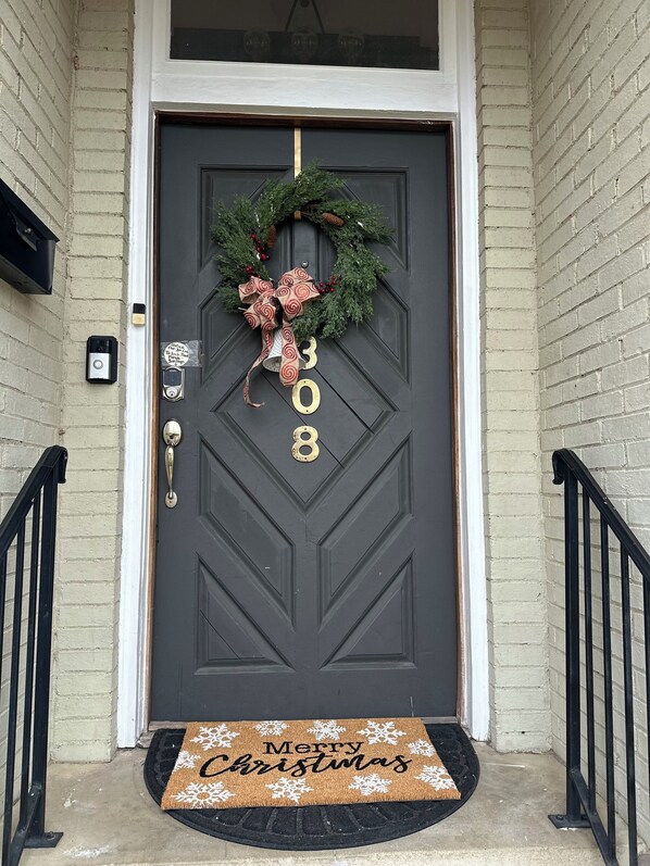 A dark gray door with a wreath and a large bow, the number 308, and a doormat with "Merry Christmas" written on it. - Montgomery Cozy Cultural Hub downtown walkable ..  sleeps 15 (Montgomery)