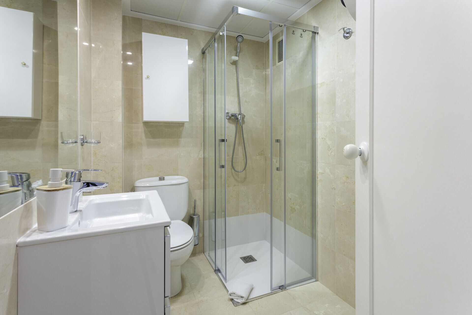 Une salle de bain moderne dotée d’une douche à parois de verre, de toilettes et d’un lavabo.