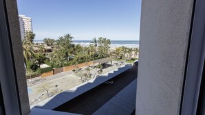 A view of a coastal area with a parking lot, palm trees, and a building in the background. - Cosy apartment decorated, with wifi, in front of the beach - only families (Playa de Gandía)