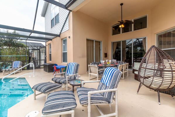 Un espacio al aire libre techado con piscina, sillas de descanso y una mesa de comedor.