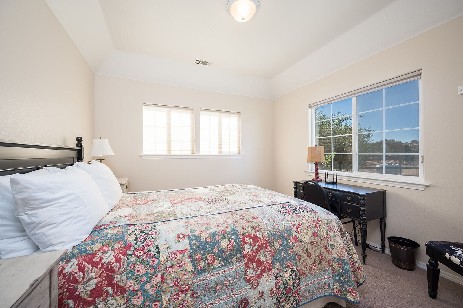 A bedroom with a bed, a desk, and a window.