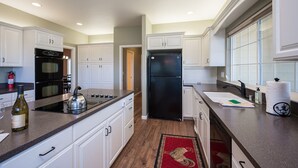 Una cocina moderna con armarios blancos, un refrigerador negro, una estufa y una botella de vino sobre la encimera.
