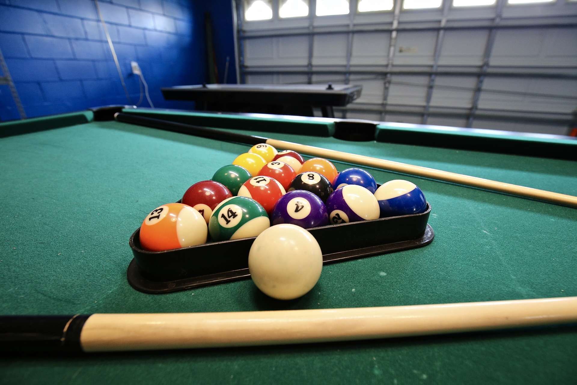 A pool table with a set of numbered balls and a cue stick.