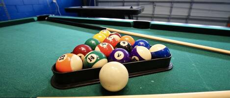 A pool table with a set of numbered balls and a cue stick.